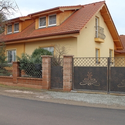 Rodinný dom oplotený kovanou bránou a bránkou so zdobenou výplňou 