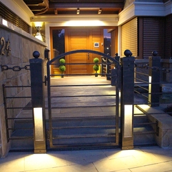 Večerný pohľad na vysvietený vstup do rodinného domu so zabudovanými svietidlami v bránke a plote