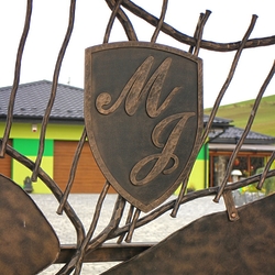 Erb s iniciálmi na dizajnovej kovanej bráne na východe Slovenska